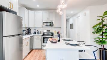 A modern kitchen with white cabinets, stainless appliances, and a central island with seating.