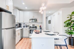 A modern kitchen with white cabinets, stainless appliances, and a central island with seating.