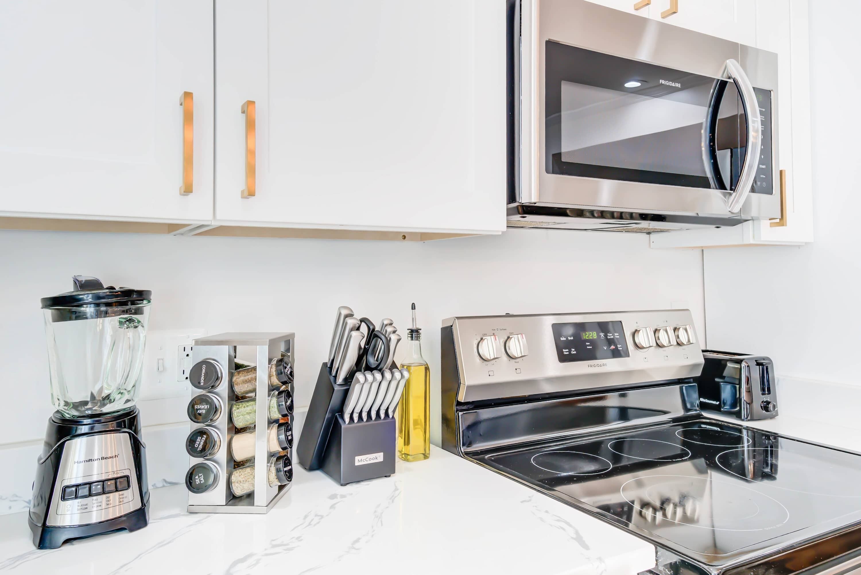 A kitchen with a blender, knife block, and a stove.