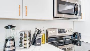 A kitchen with a blender, knife block, and a stove.