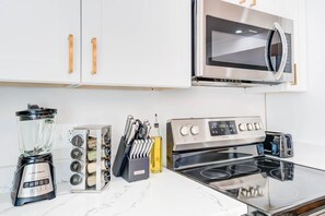 A kitchen with a blender, knife block, and a stove.