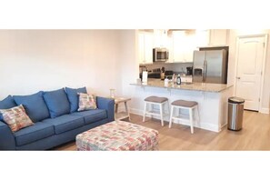 Relax in this cozy living space with a sofa, ottoman, and kitchenette.