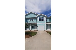 Stunning two-story home with a central entrance and double garage door, set amidst a beautifully manicured lawn.