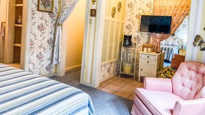 A bedroom with a bed, a chair, a television, and a dresser.