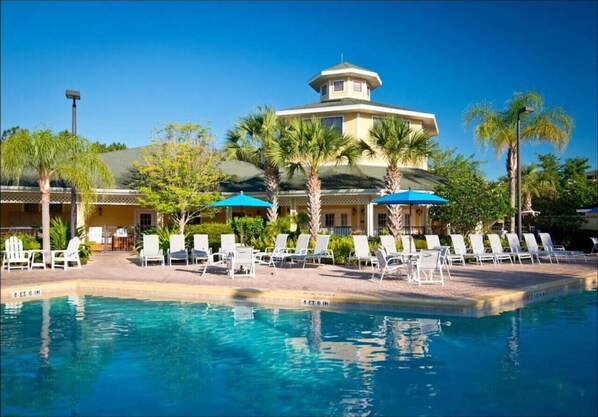Relax by the resort pool surrounded by palm trees and lounge chairs.