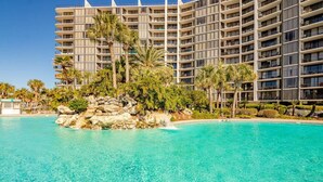 A hotel with a large pool, palm trees, and a rocky island in the center. - Gulf-View Balcony at Edgewater Resort (Panama City Beach)