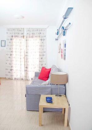 Une petite pièce accueillante, avec un canapé à carreaux, une petite table et une lampe.