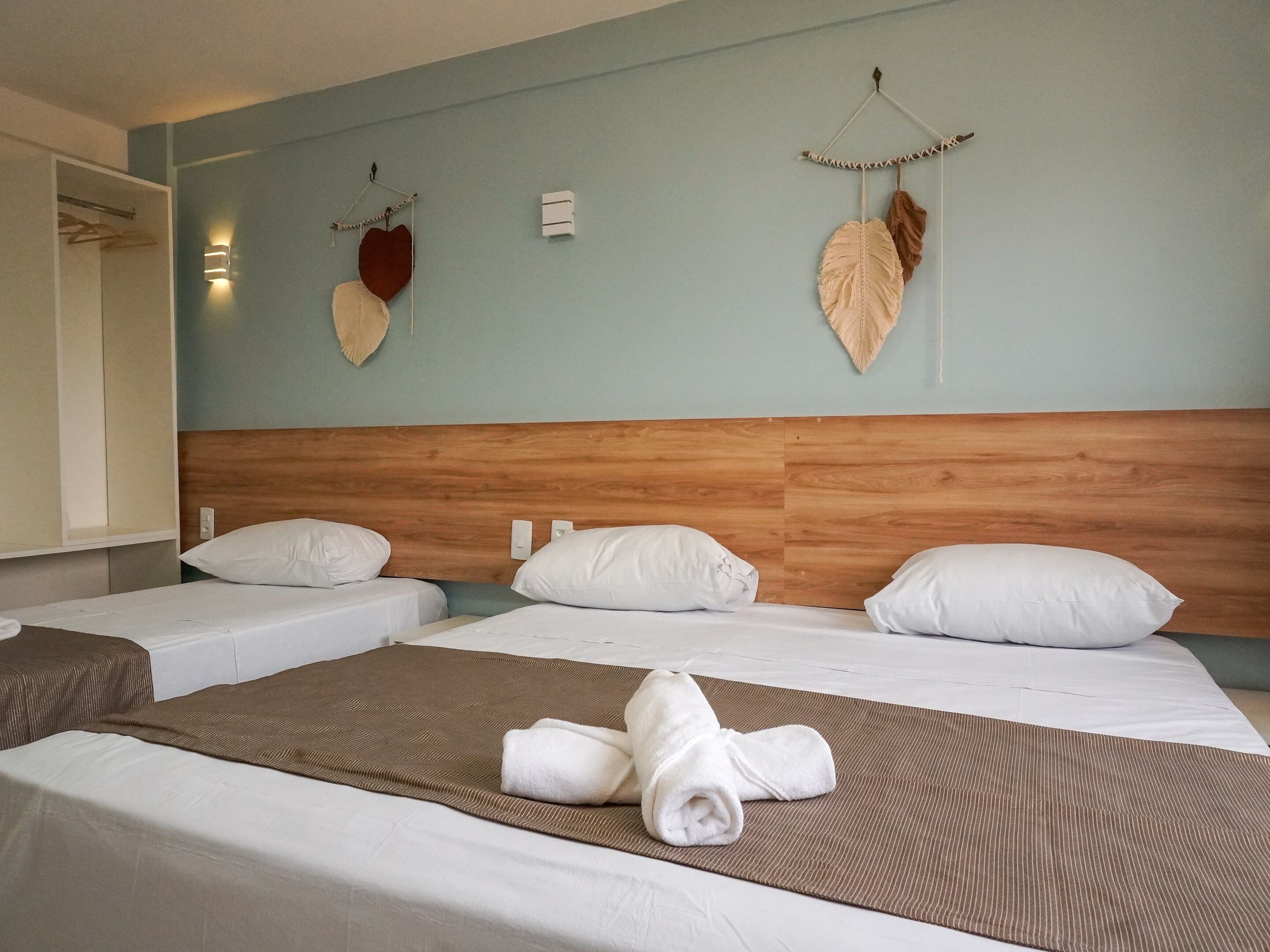 Una habitación de hotel con dos camas individuales, un cabecero de madera y adornos decorativos en la pared.