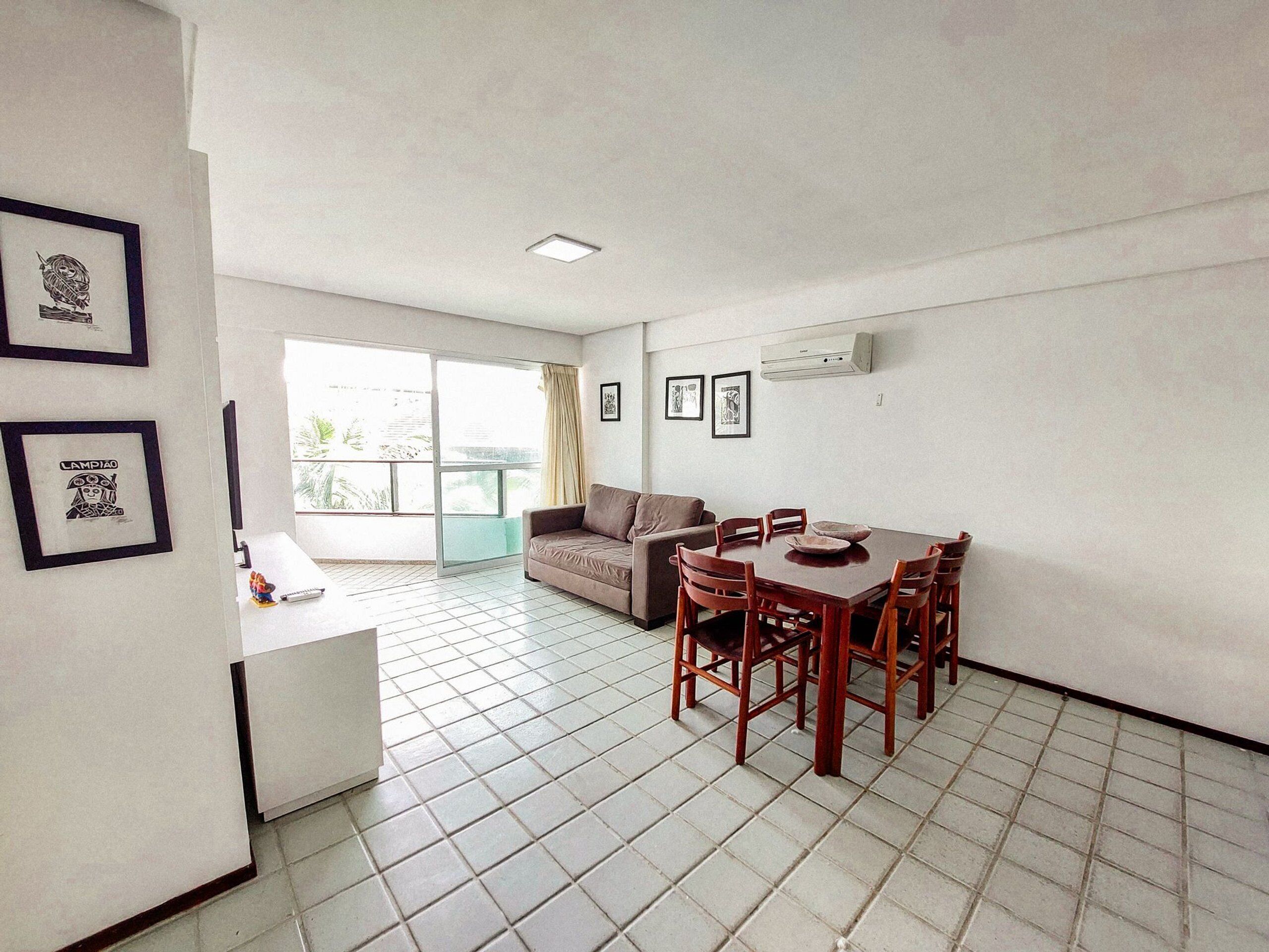 A dining area with a table and chairs, a sofa, and a window with a view.