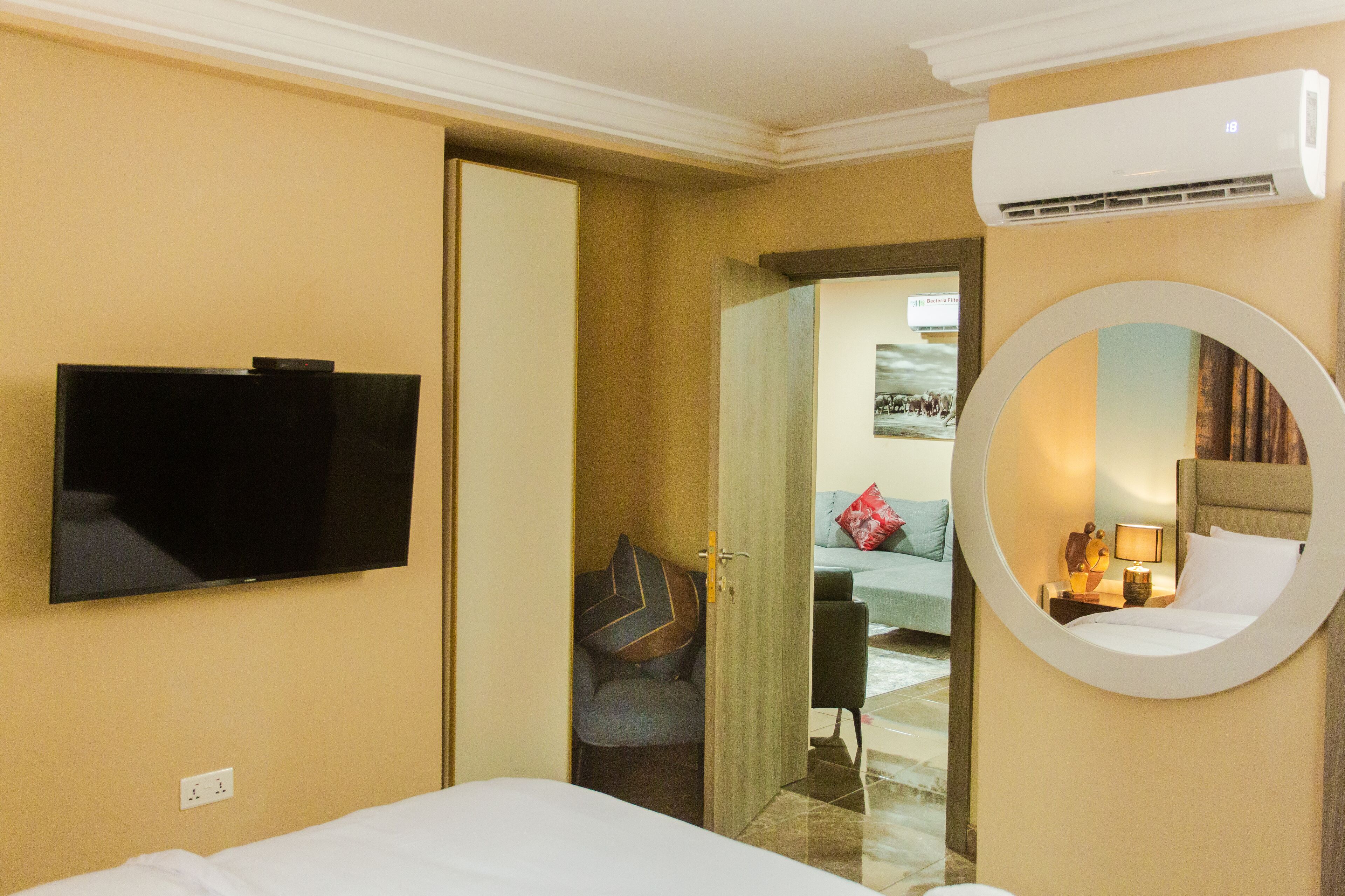 Une chambre d’hôtel équipée d’un lit, d’un téléviseur fixé au mur, d’un miroir rond et d’un appareil de climatisation.