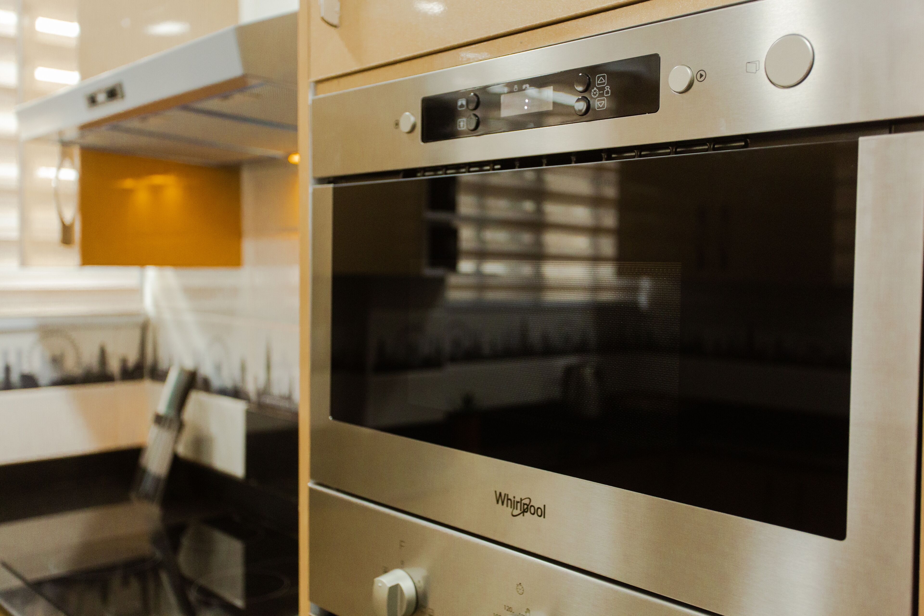 Un horno Whirlpool de acero inoxidable con panel de control digital, ubicado en una cocina moderna con una pared de acento amarilla.