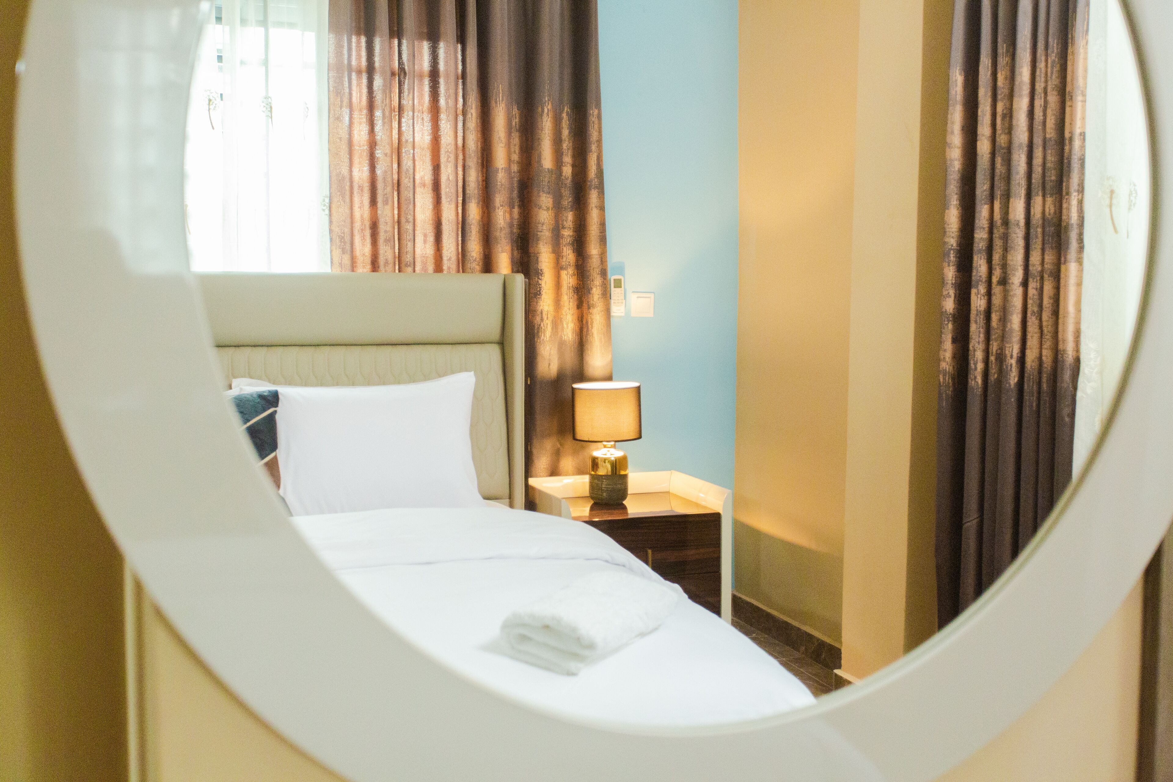 Una habitación de hotel con cama, mesita de noche y cortinas.