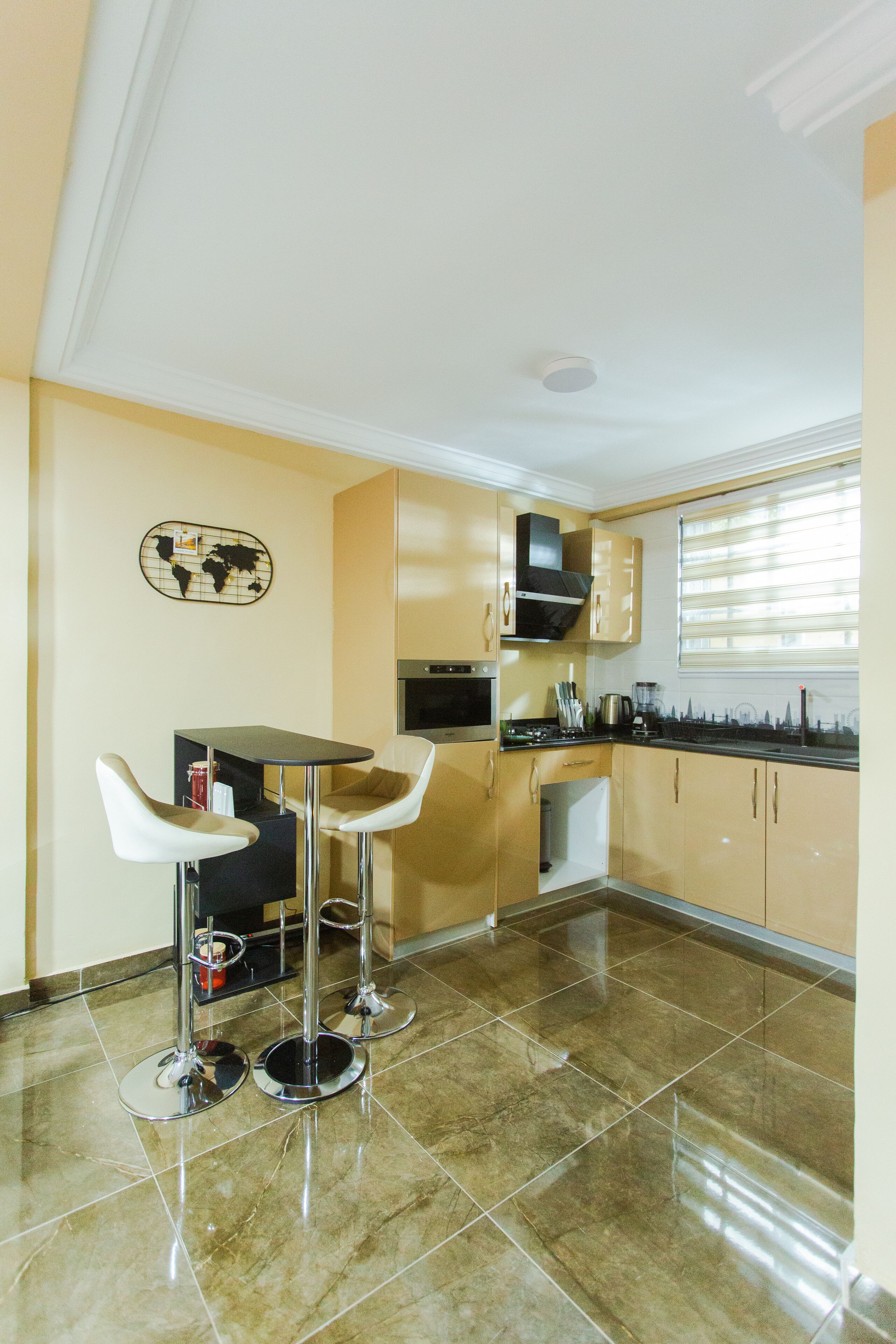 A compact kitchen with two bar stools, a microwave, a stove, and a small refrigerator.