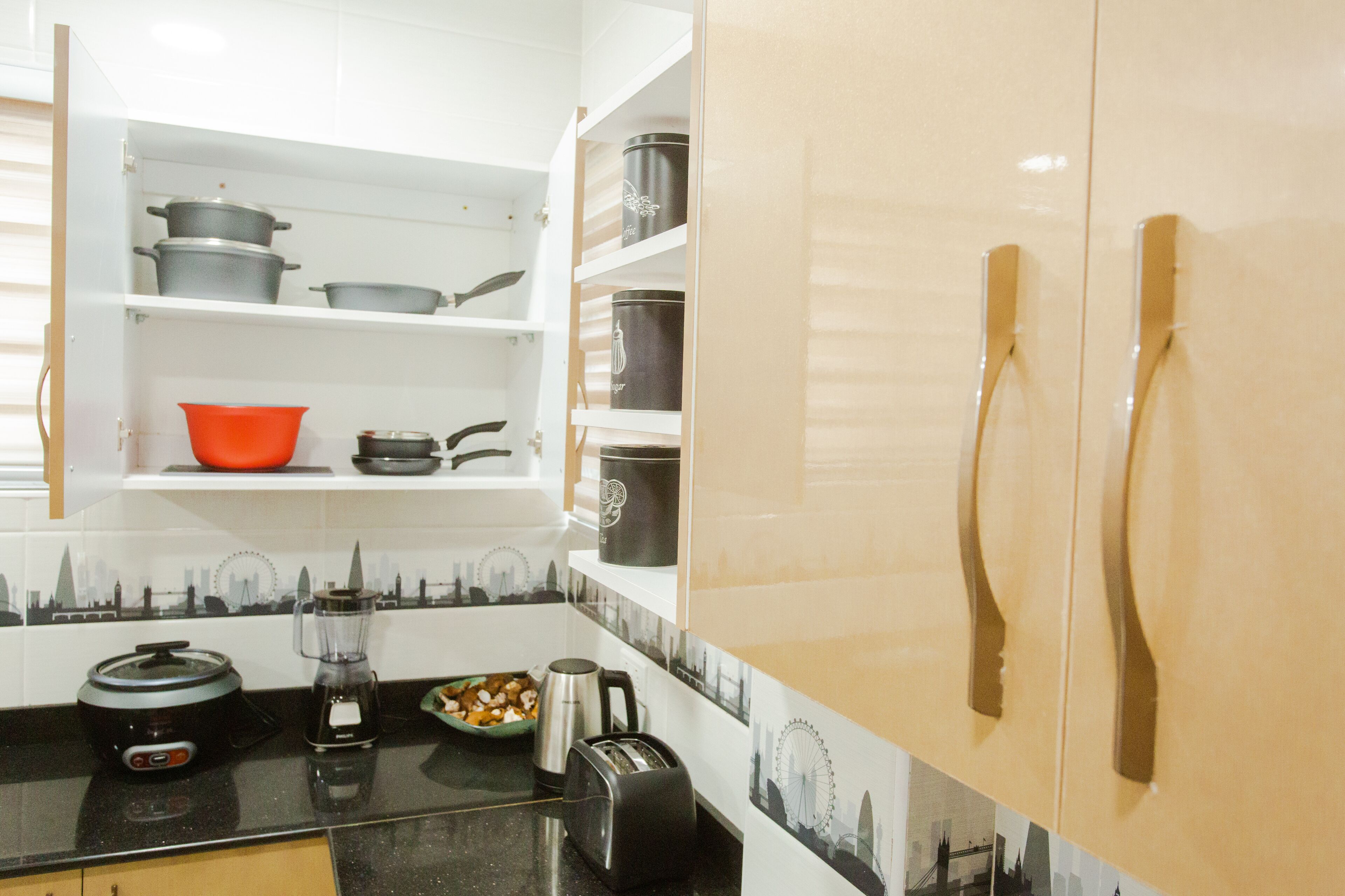 A kitchen with white cabinets, a black countertop, and a cityscape backsplash.