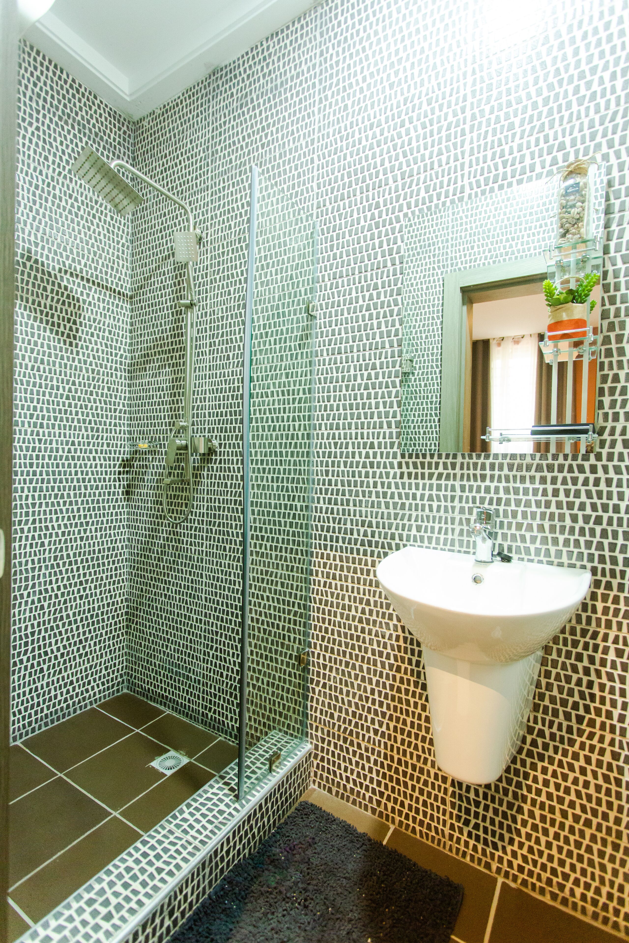 A bathroom with a shower, a sink, and a mirror.