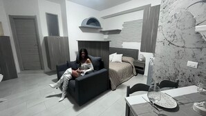A modern bedroom with a bed, a sofa, a dining table, and a kitchen area. - Nina's house 3 300 meters from the sea (Santa Caterina Dello Ionio Marina)