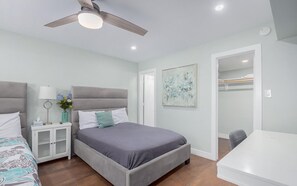 Ein Schlafzimmer mit Bett, Nachttisch, Lampe und Kunstwerk.