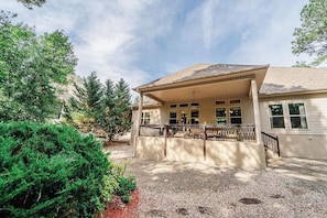 A building with a covered porch, a gravel driveway, and surrounding greenery. - Quiet, Beautiful Home Nestled in the woods (Hot Springs Village)