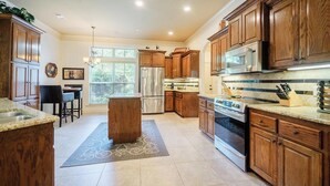 A modern kitchen with wooden cabinets, stainless steel appliances, and a central island. - Quiet, Beautiful Home Nestled in the woods (Hot Springs Village)