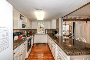 Kitchen area with microwave, stovetop, oven, and sink.