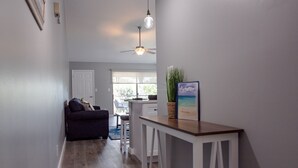 Un salon moderne avec un canapé foncé, une table basse et un coin repas comprenant une table et des chaises en bois.