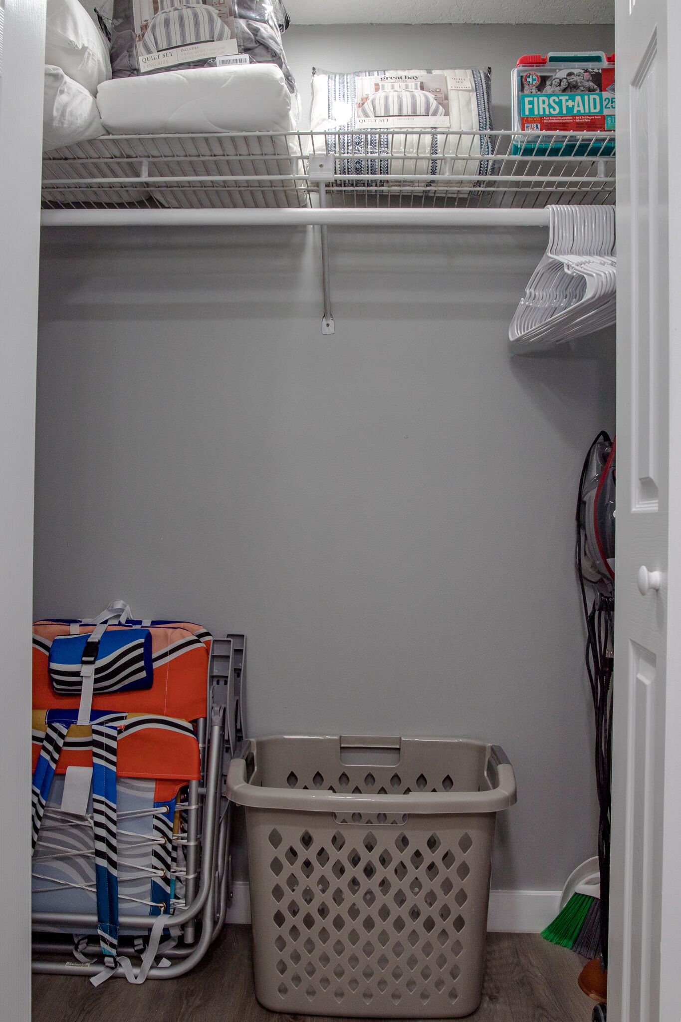 Een wasruimte met een wasmachine, een droogrek en een opbergplank met schoonmaakmiddelen.