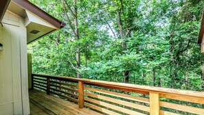 Une terrasse en bois dotée d’une rambarde, qui offre une vue sur une forêt dense.