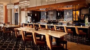 Un área de bar con diversas opciones de asientos, incluyendo mesas y taburetes.
