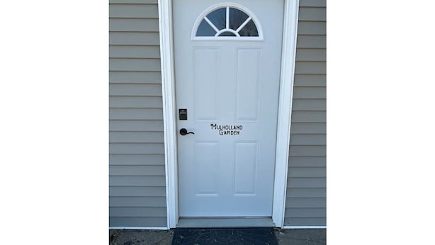 A white door with a small window and the text "Mulholland Garden" on it.