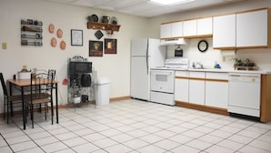 A kitchen with white cabinets, a stove, microwave, and a dining area with a table and chairs.