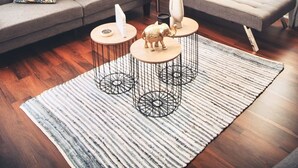 Uma sala de estar moderna com um sofá, poltrona e duas mesas redondas com objetos decorativos.
