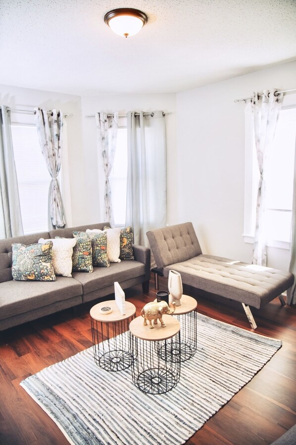 Una sala de estar moderna con un sofá, un sillón y dos mesas redondas decoradas.