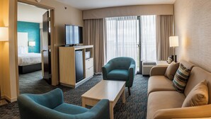 Habitación de hotel con cama, escritorio con computadora, televisor, sofá y sillón.