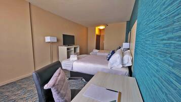 A hotel room with two beds, a desk with a chair, a television, and a mirror.