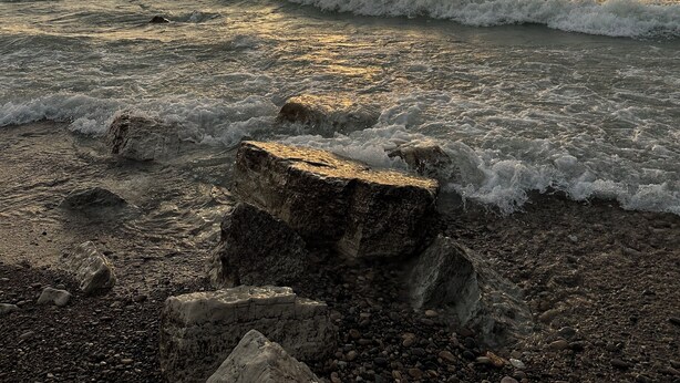 Una costa rocosa con olas al atardecer.