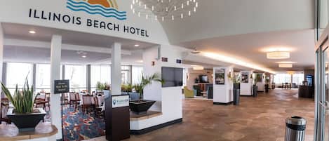 Vestíbulo del Illinois Beach Hotel con una recepción, zona de estar y un ventanal grande.