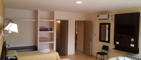 Habitación de hotel con dos camas, un escritorio con teléfono, una silla, televisor, armario y espejo.