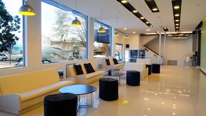 En moderne lobby med siddeområder, store vinduer og et rent, spejllignende gulv.