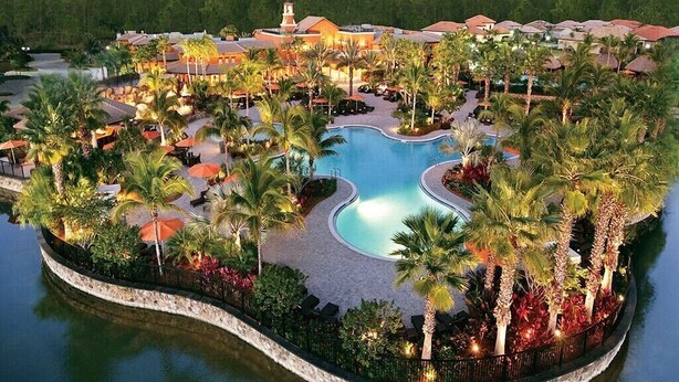 A resort with a central swimming pool, surrounded by palm trees and lounge areas.