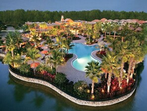 A resort with a central swimming pool, surrounded by palm trees and lounge areas. - Paseo Ft. Myers 3BR Gated Luxury Condo Winter 2027 (Fort Myers)