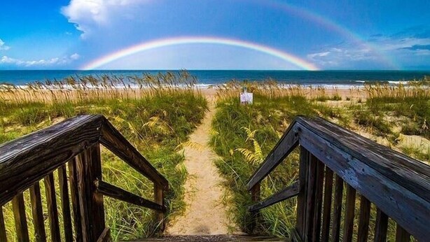 A wooden pathway leading to a beach with a rainbow in the distance. - Golf Cart to Beach, Pet Friendly, Fenced Yard, Amelia Island Quiet Home Escape (Fernandina Beach)