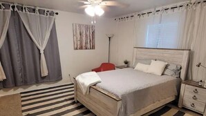 A bedroom with a bed, a bedside table, a nightstand, a floor lamp, a painting, and curtains. - Traveller's peaceful paradise (Muskogee)
