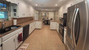 A modern kitchen with white cabinets, stainless steel appliances, and a central island. - Traveller's peaceful paradise (Muskogee)