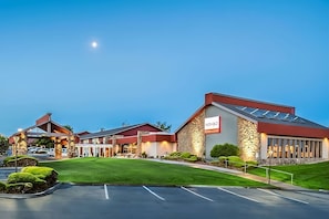 A hotel with a modern design, featuring a prominent 'NOMAD' sign, a parking lot, and well-maintained landscaping. - Comfort Meets Affordability, Free Parking, Outdoor Pool, Pets Allowed (Kennewick)