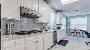 Una cocina moderna con armarios blancos, una estufa de acero inoxidable y un lavavajillas.