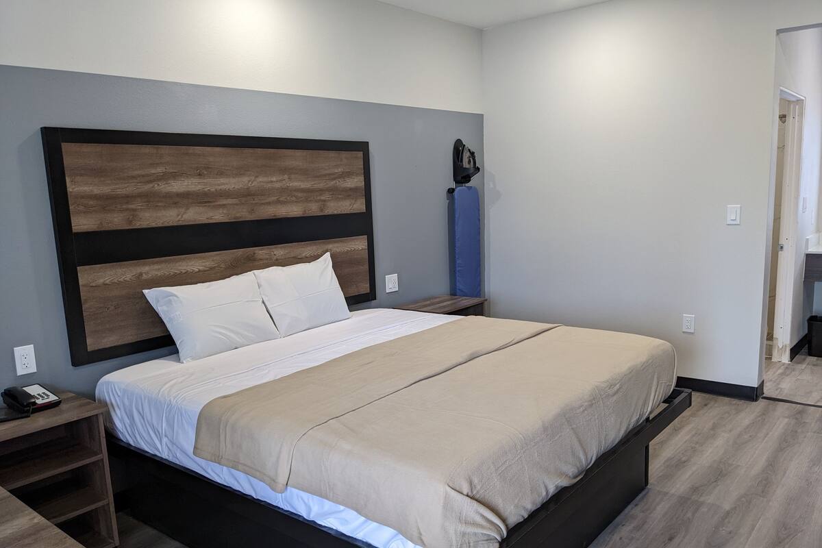 A modern bedroom with a large bed, wooden headboard, bedside tables, and a built-in wardrobe.