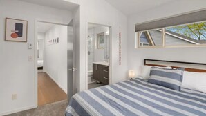 Una camera da letto con un letto, un comodino, uno specchio e una finestra che offre vista sull'esterno.