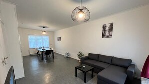 A modern living room with a sectional sofa, a coffee table, and a dining area with a table and chairs.