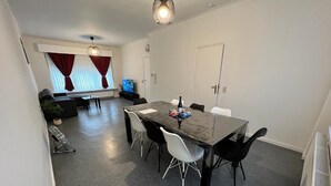 A dining area with a rectangular table, six chairs, and a television in the background.