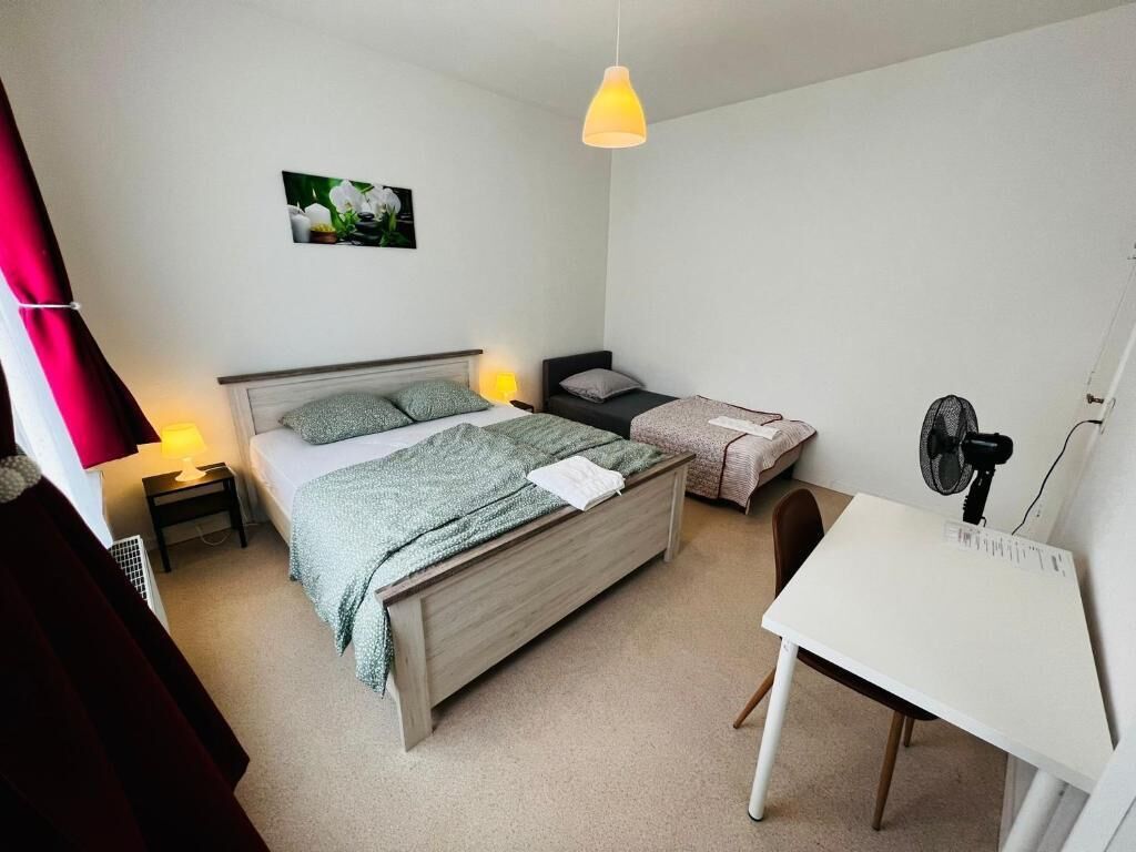 A bedroom with a bed, bedside tables, a desk, and a chair.
